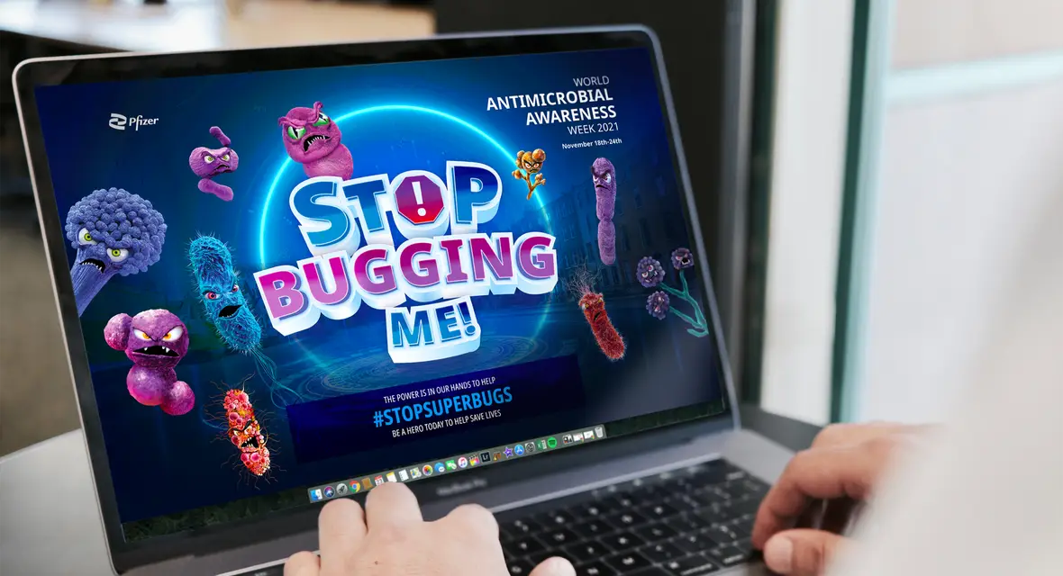 Zoomed in shot of someone at a laptop, on the screen is a website we did for World Antimicrobial Awareness Week alongside Pfizer, the website shows animated super bugs moving on the screen.